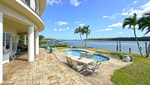 A pool area with a view of the water, outdoor furniture, and a covered patio. - Sandman's Haven Retreat (Stuart)