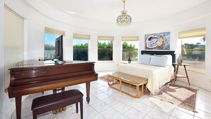 A spacious bedroom with a piano, a bed with a view, and a chandelier. - Sandman's Haven Retreat (Stuart)