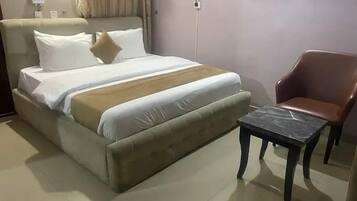 A bed with a headboard, a bedside table, and a chair.
