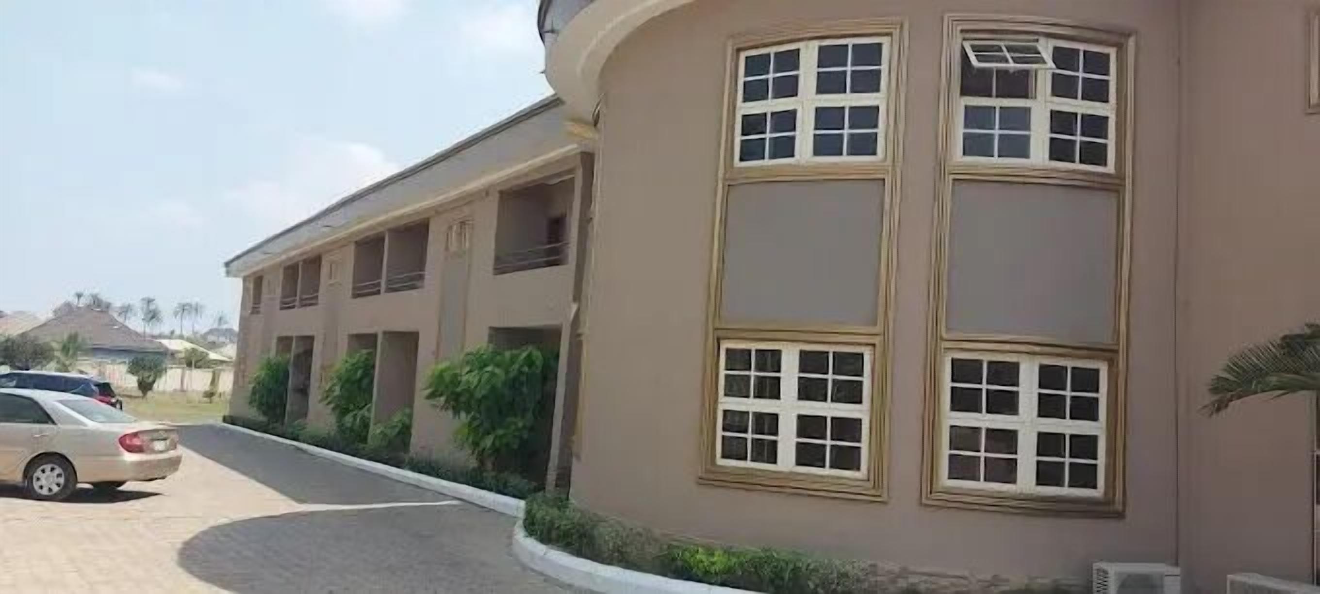 A multi-story building with a curved facade, large windows, and a driveway.
