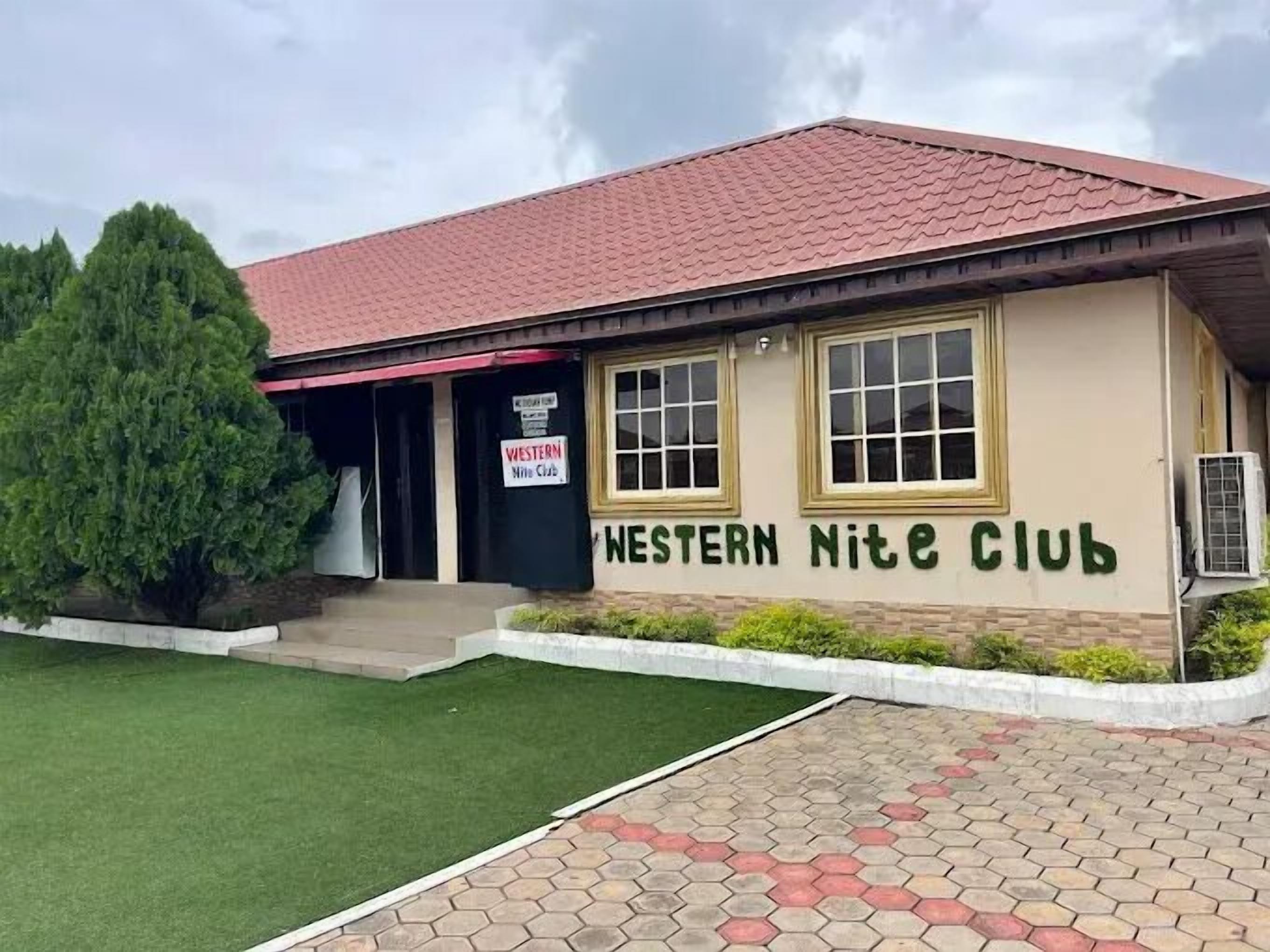 Een gebouw met een rood pannendak en een bord waarop staat: Western Nite Club.