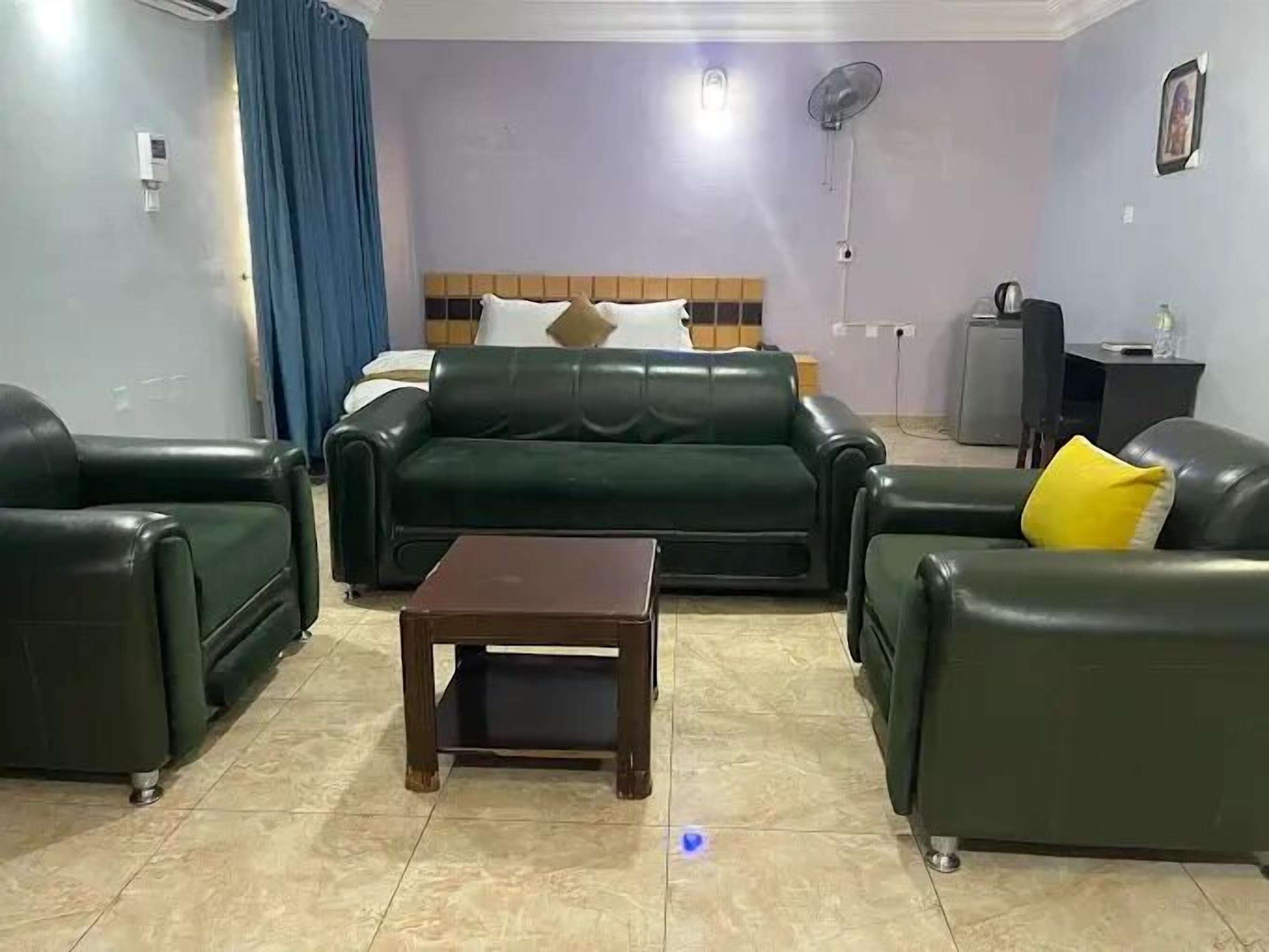 Una sala de estar con un sofá verde, una mesa de centro de madera y una cortina azul.