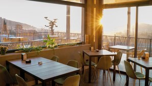 A restaurant with large windows, wooden tables, and green chairs. - Hotel Vita (Salò)