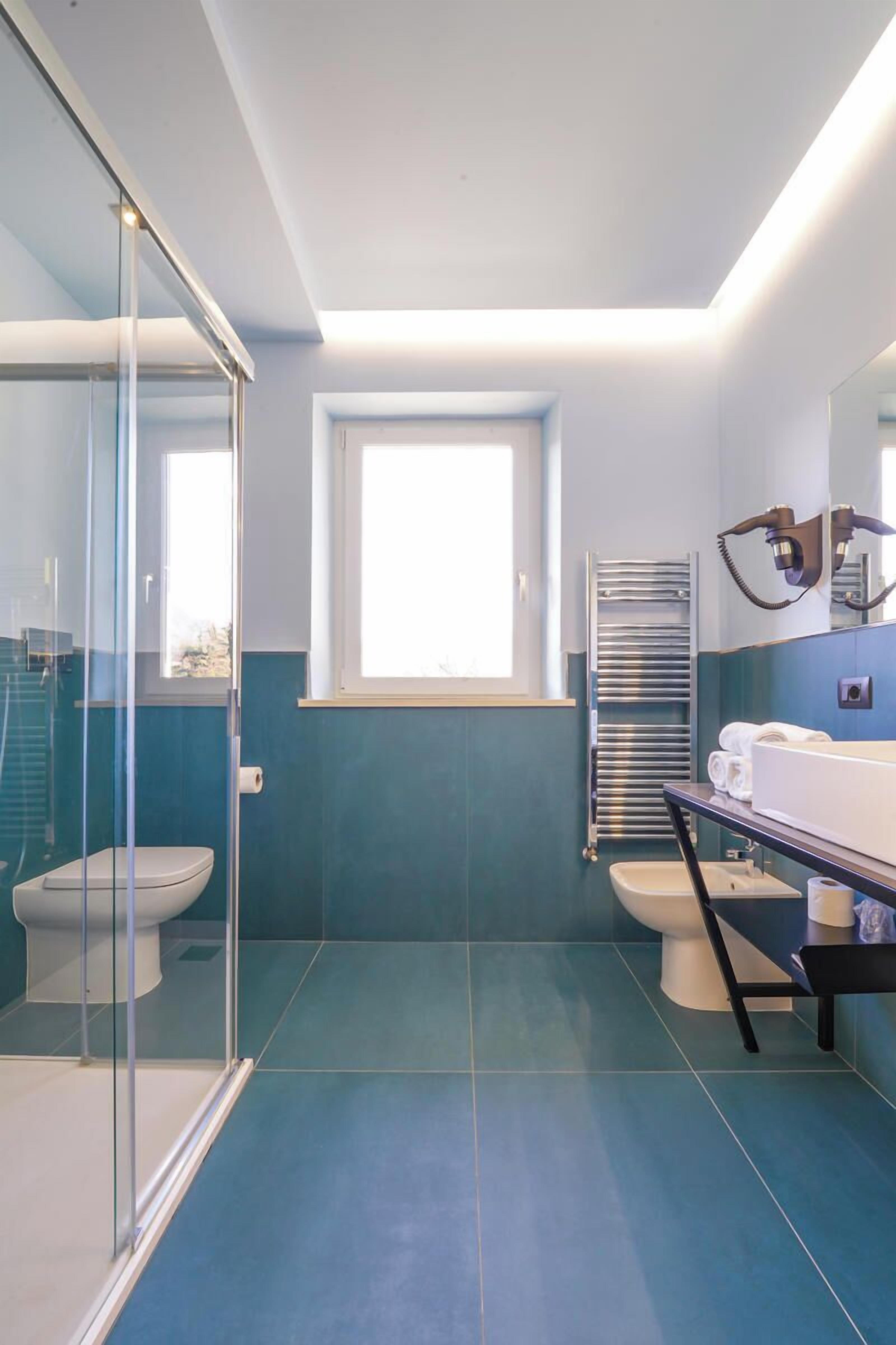 A modern bathroom with a glass shower enclosure, a window, and a vanity with a towel rack.