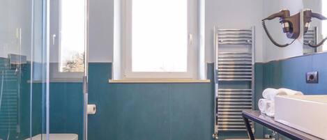A modern bathroom with a glass shower enclosure, a window, and a vanity with a towel rack.