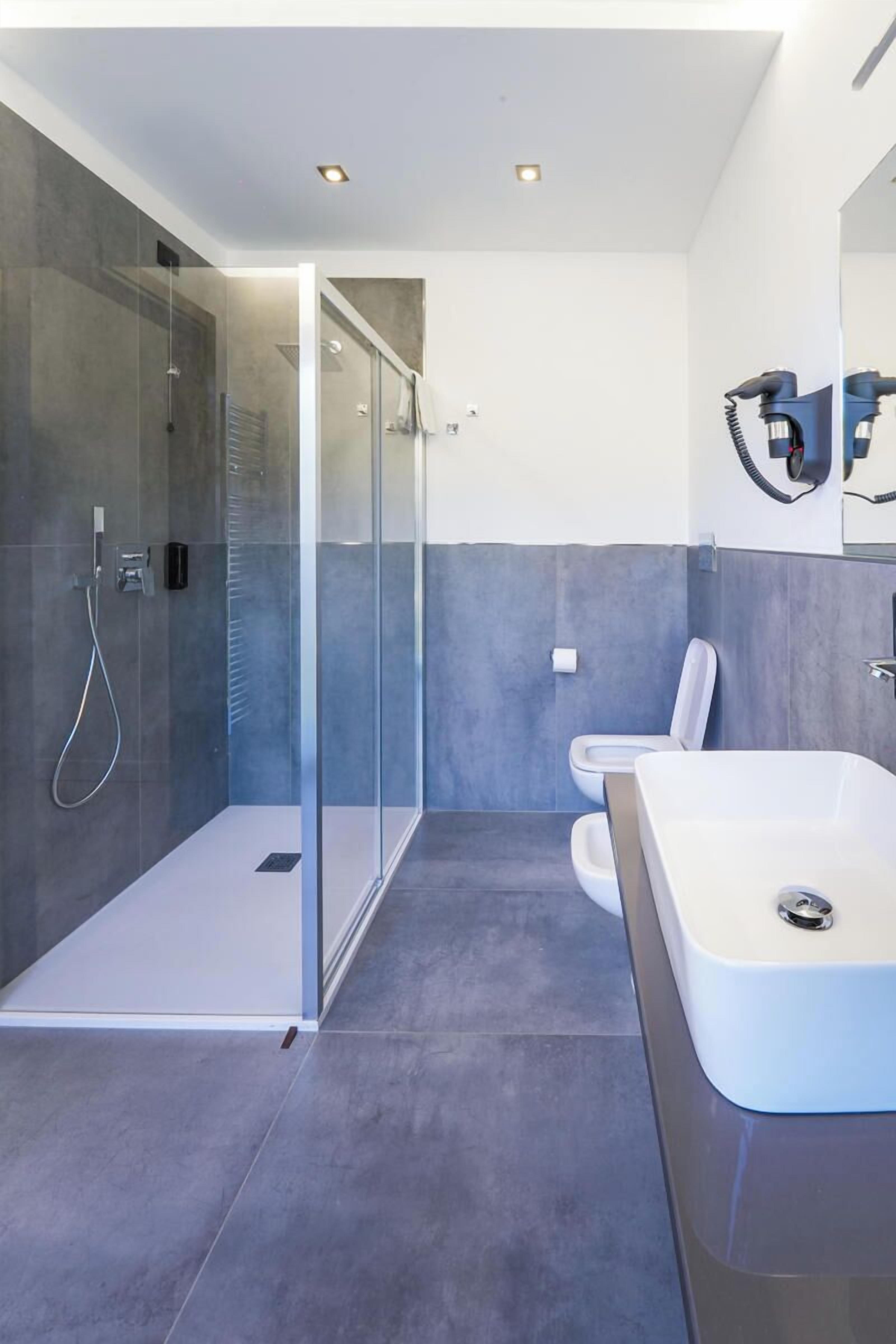 A modern bathroom with a glass-enclosed shower, a white sink, and a toilet.
