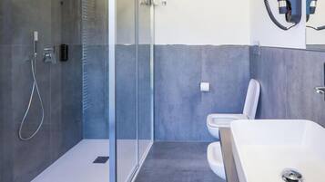 A modern bathroom with a glass-enclosed shower, a white sink, and a toilet.
