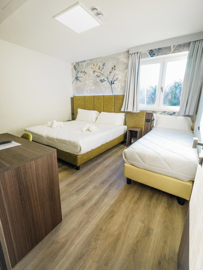 Een hotelkamer met een bed, bureau en een raam met gordijnen.