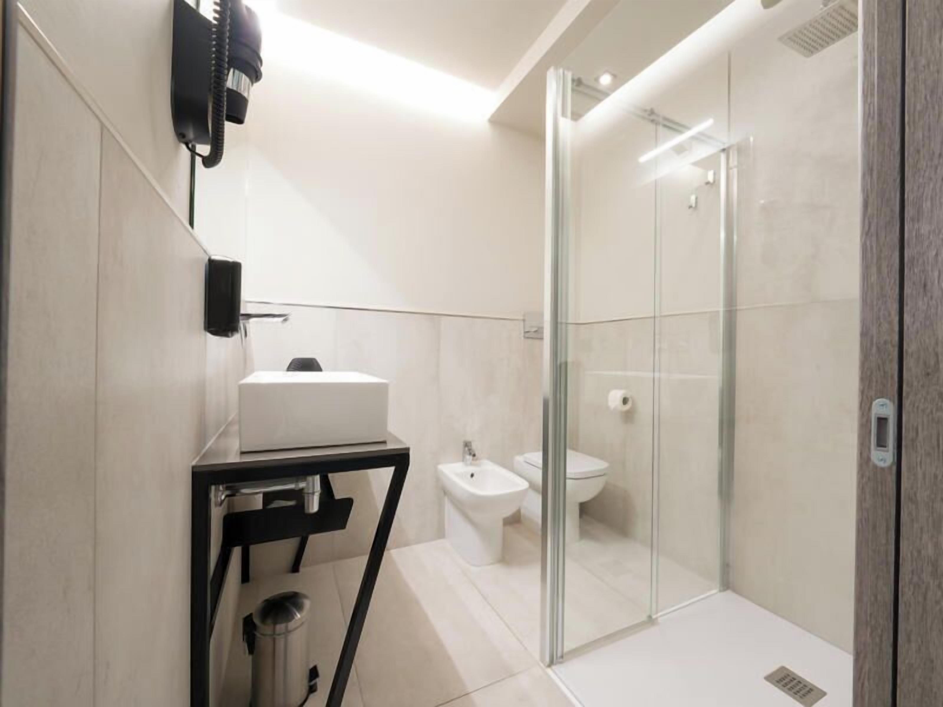 A modern bathroom with a glass shower enclosure, a sink, and a bidet.