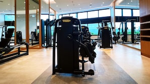Een moderne sportschool met diverse fitnessapparaten, grote ramen en een ruim, schoon interieur.