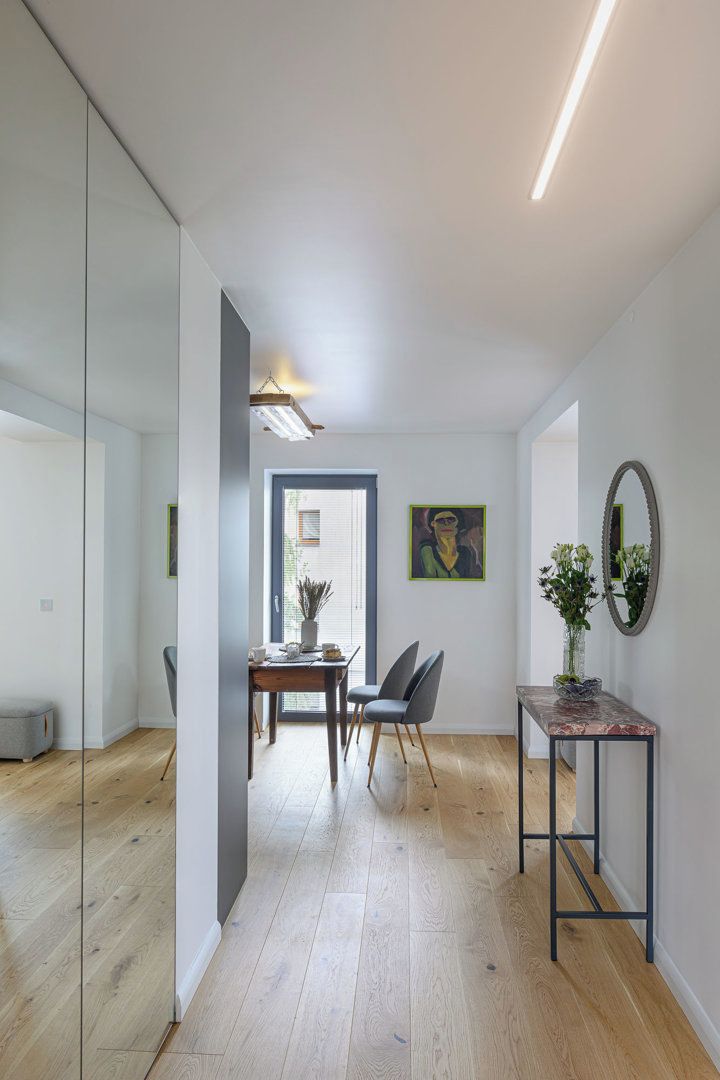 A modern interior with a dining area, a mirror, and a plant.