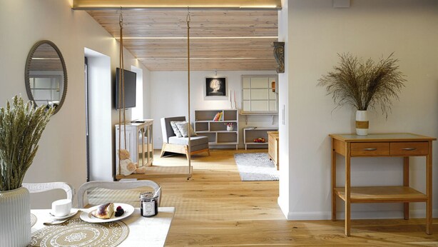 Una sala de estar moderna con techo de madera, un sofá, un televisor y un comedor con mesa y sillas.