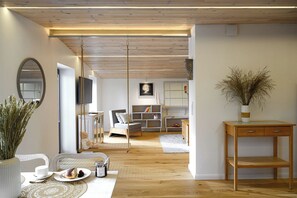 Un salon moderne avec un plafond en bois, un canapé, un téléviseur et un coin repas comprenant une table et des chaises.