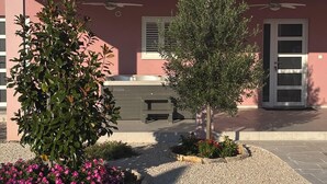 A building with a pink facade, a small garden with gravel and pink flowers, and a door with a glass panel. - Villa Rosea Domus Zadarvillas (Benkovac)