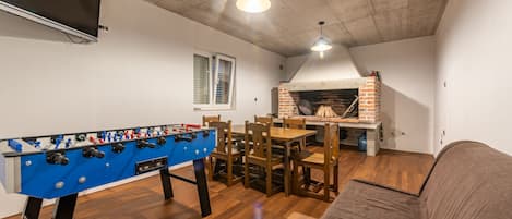 A cozy living room with a foosball table, a brick fireplace, and a television mounted on the wall.