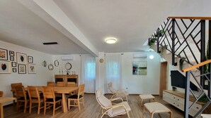 A spacious living area with a wooden dining table, chairs, a sofa, and a staircase with a geometric railing. - Villa Rosea Domus Zadarvillas (Benkovac)