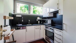 Eine moderne Küche mit weißen Schränken, einer schwarzen Arbeitsplatte, einem eingebauten Backofen und einer Mikrowelle.