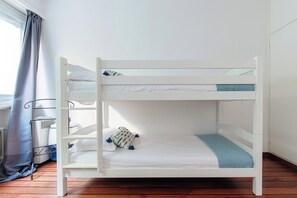 Un lit superposé avec une literie blanche et un oreiller bleu.