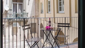 Ein Balkon mit Tisch, Stühlen und einer Weinflasche.