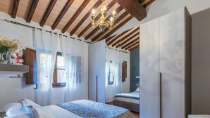 A bedroom with a bed, a wardrobe, a hanging light fixture, and a window with curtains.