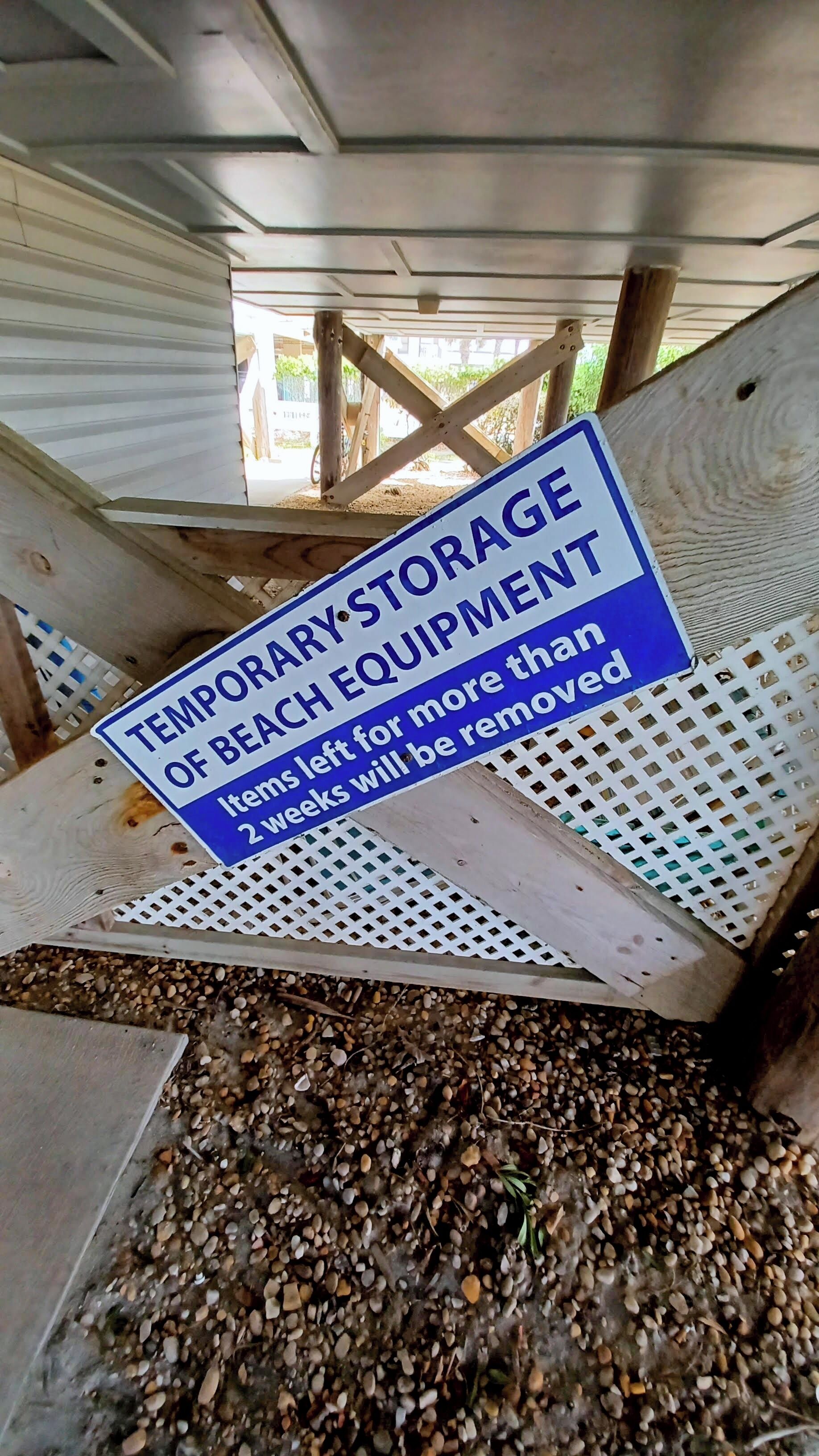 A sign indicating temporary storage of beach equipment with a warning that items left for more than two weeks will be removed.