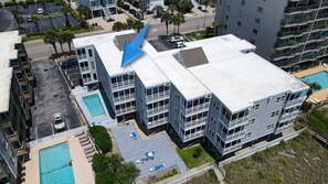 A multi-story hotel with a rooftop pool and a parking lot.