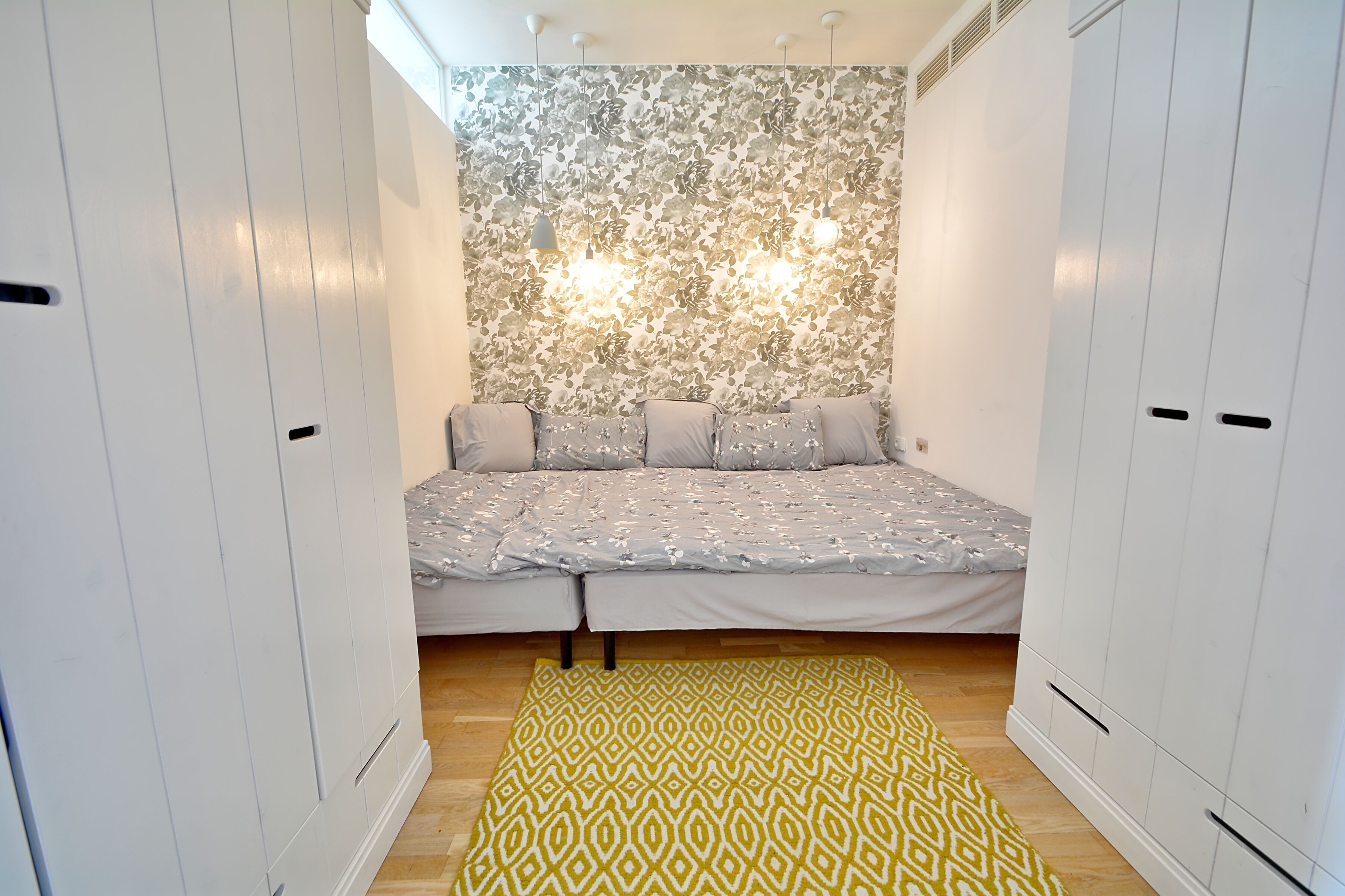 Ein Schlafzimmer mit Bett, Kleiderschrank und einem gemusterten Teppich.