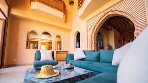 A spacious living area with a teal sofa, a marble coffee table, and a woven hat. - Villa Dar Minzah (Aghouatim)
