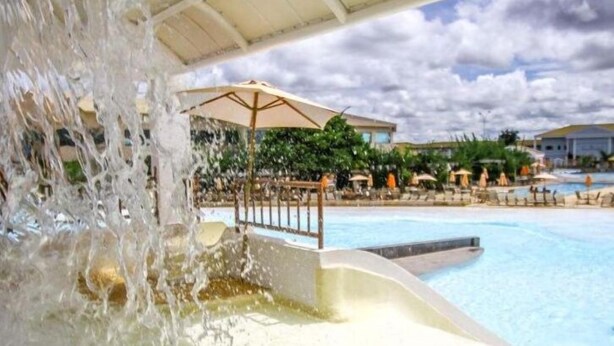 A water slide leading into a pool with umbrellas and lounge chairs in the background. - LH Lacqua diRoma (Caldas Novas)