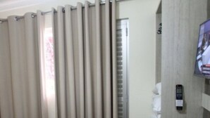 A hotel room with a bed, curtains, a television, and a remote control on the wall. - LH Lacqua diRoma (Caldas Novas)