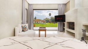 Une chambre moderne dotée d’une grande fenêtre, d’un téléviseur à écran plat, d’un canapé et d’une cheminée.