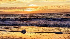 Une plage avec des vagues et un coucher de soleil.
