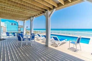 A covered deck with a pool, lounge chairs, and a view of the ocean. - Ziggy's Place - New Luxury 8 BR Oceanfront Home; Pool & Elevator! (Surf City)