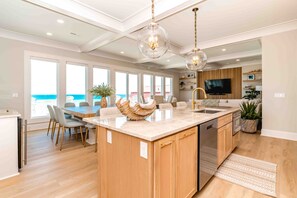 A modern kitchen with a large island, wooden cabinets, and a view of the ocean. - Ziggy's Place - New Luxury 8 BR Oceanfront Home; Pool & Elevator! (Surf City)