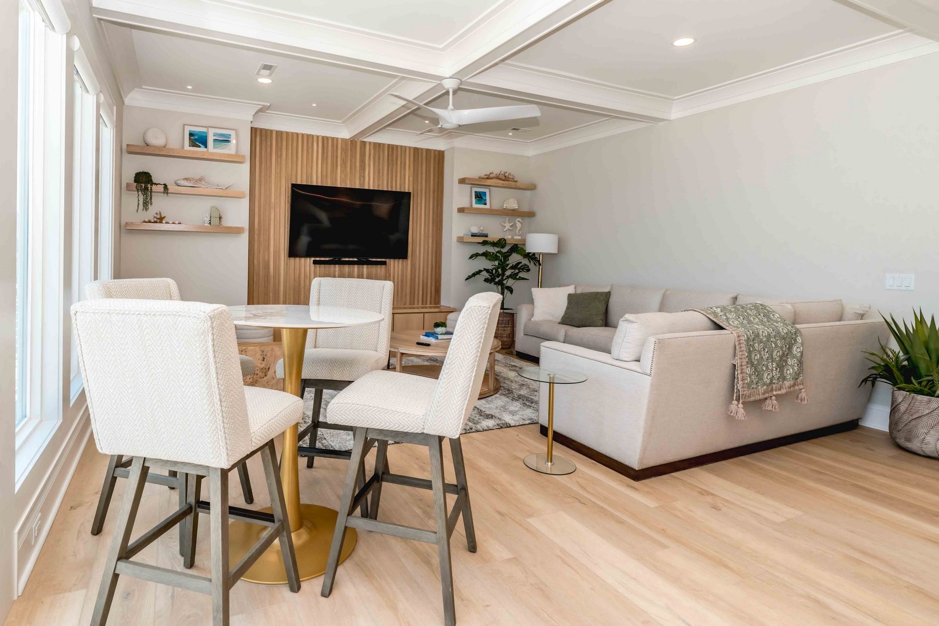 Un salon moderne avec un canapé, des fauteuils, une table basse, un téléviseur et un plancher en bois.