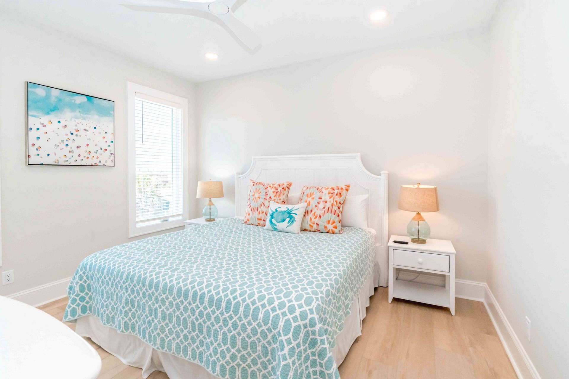 A bedroom with a bed, two bedside tables, a window, and a ceiling fan.