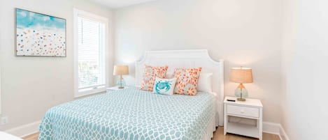 A bedroom with a bed, two bedside tables, a window, and a ceiling fan.