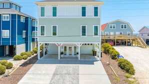 A two-story house with a covered front porch and a garage. - Ziggy's Place - New Luxury 8 BR Oceanfront Home; Pool & Elevator! (Surf City)