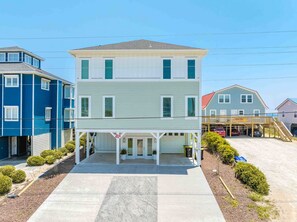 A two-story house with a covered front porch and a garage. - Ziggy's Place - New Luxury 8 BR Oceanfront Home; Pool & Elevator! (Surf City)