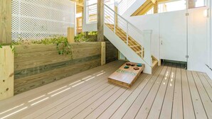 A wooden deck with a wooden bench and a small table with a game. - Ziggy's Place - New Luxury 8 BR Oceanfront Home; Pool & Elevator! (Surf City)