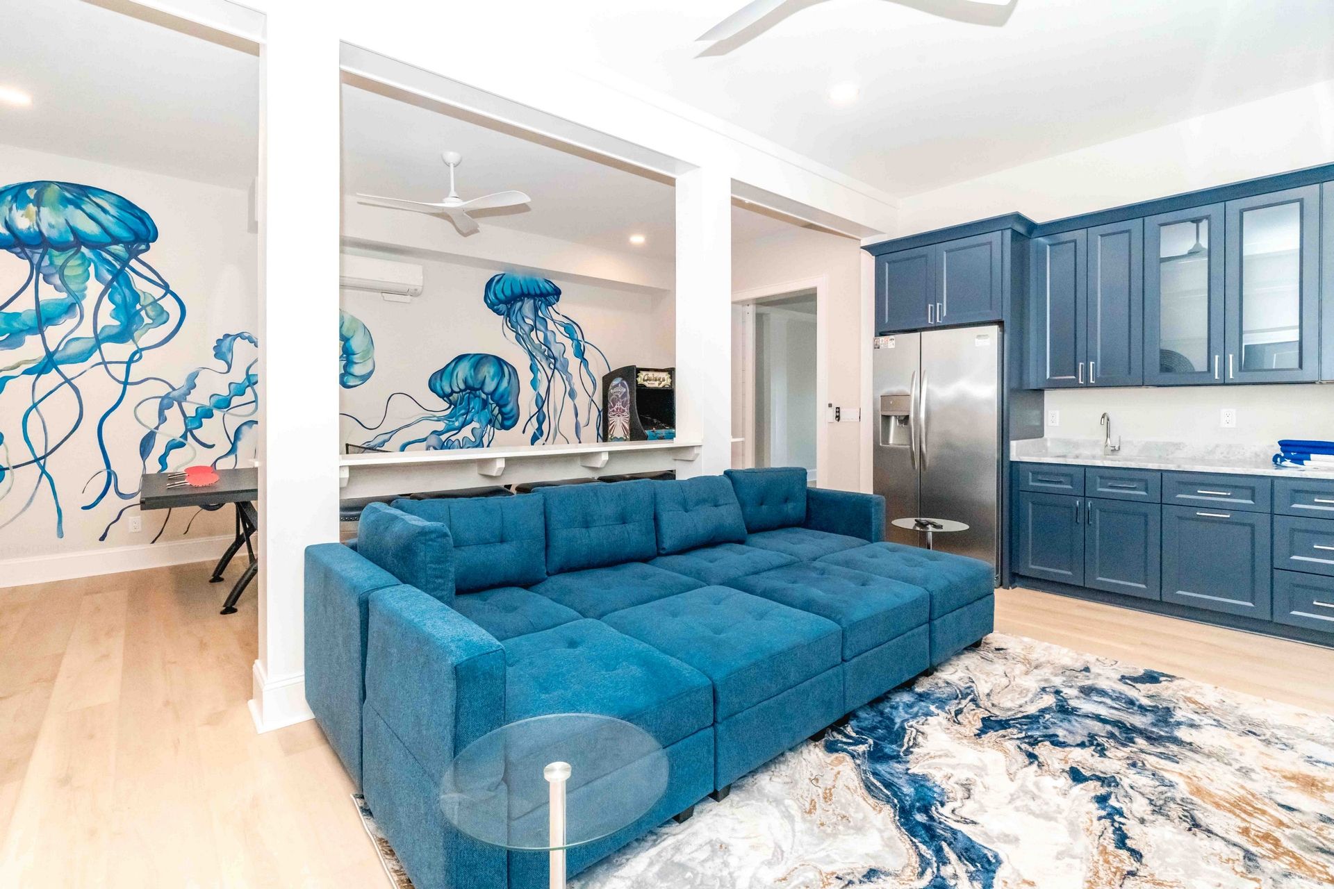 Eine moderne Küche mit blauen Schränken, einem Edelstahlkühlschrank und einem blauen Sofa im Wohnbereich.