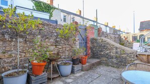A stone wall with potted plants and a metal table. - Ashley Suite by Koya Homes (Vale of Glamorgan)