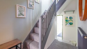 A staircase with patterned steps, a wooden bench, and framed artwork on the walls. - Ashley Suite by Koya Homes (Vale of Glamorgan)