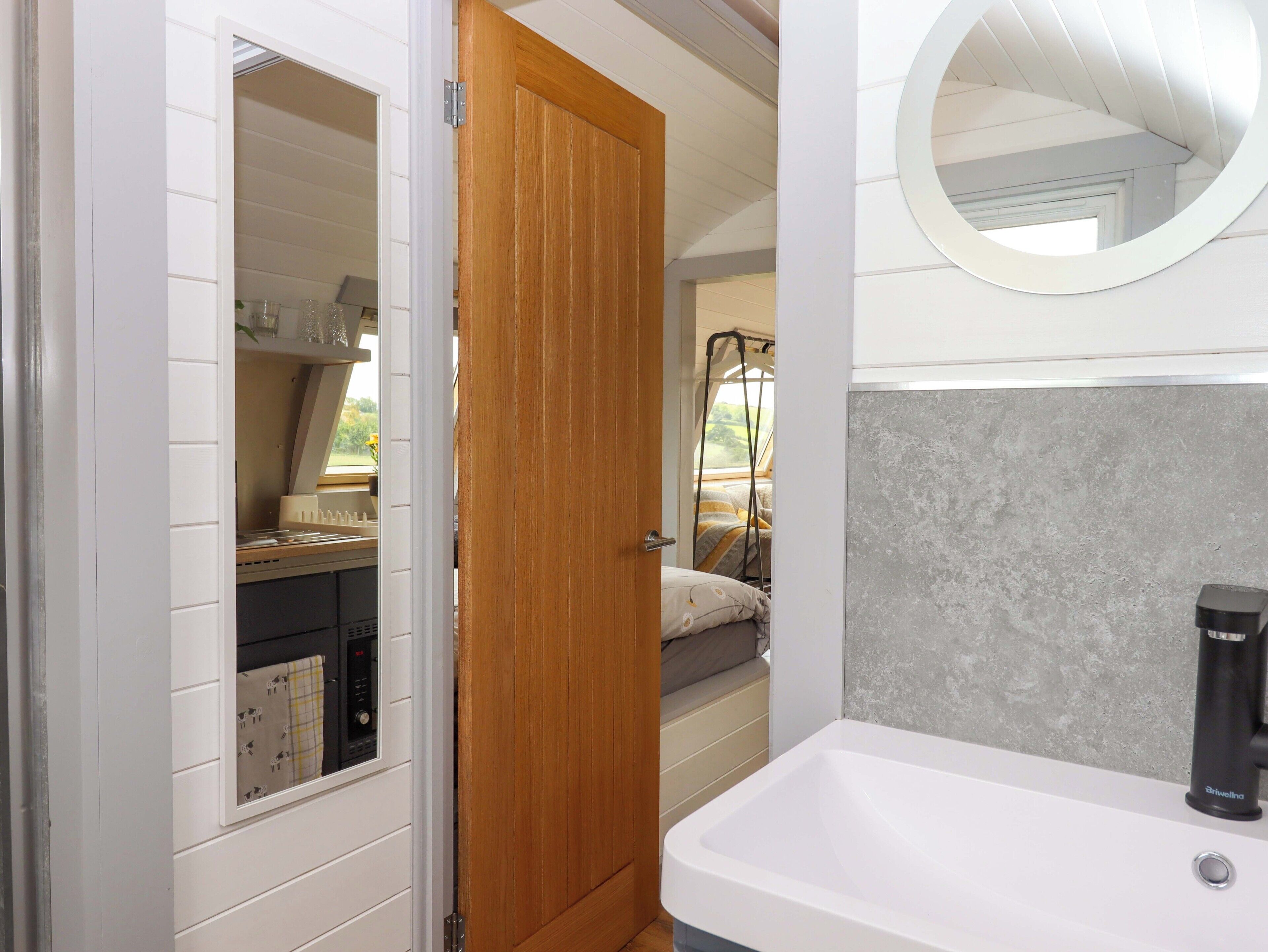 A compact bathroom with a white sink, a mirror, and a shower area.