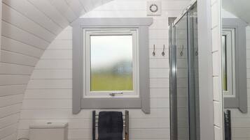 Un baño con tragaluz, barra para toallas y mampara de vidrio.