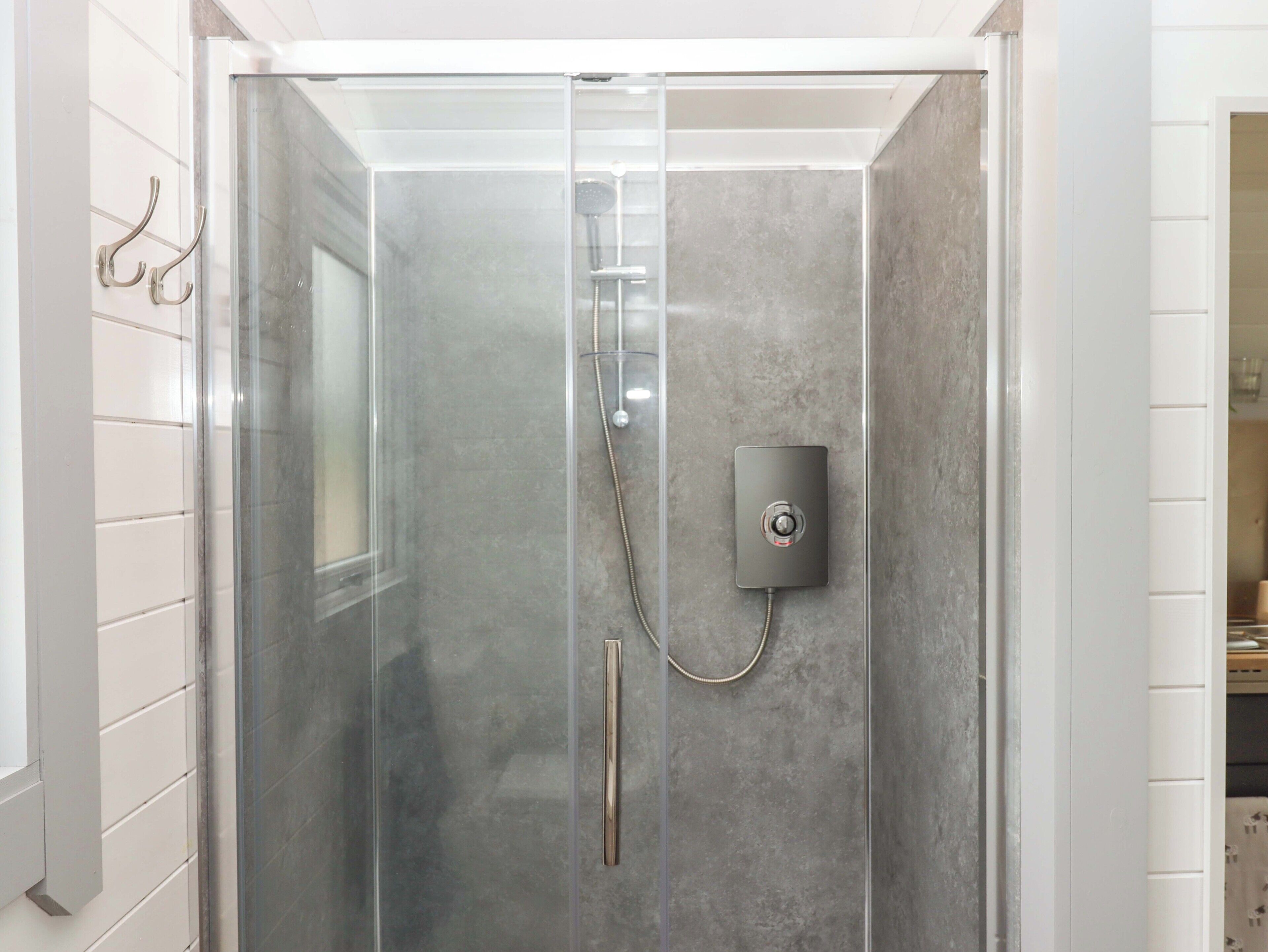 Ducha con mampara de vidrio, panel de control y toallero.