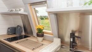 A modern kitchen with a built-in window, stainless steel appliances, and a drying rack. - Under Oak Pod (Totnes)