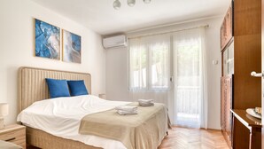 A bedroom with a bed, bedside tables, a wardrobe, and a window with curtains. - Apartment Seaside (Unknown)