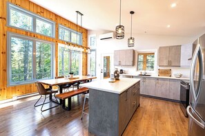 A modern kitchen with wooden cabinetry, a large island, and a dining area with a bench.