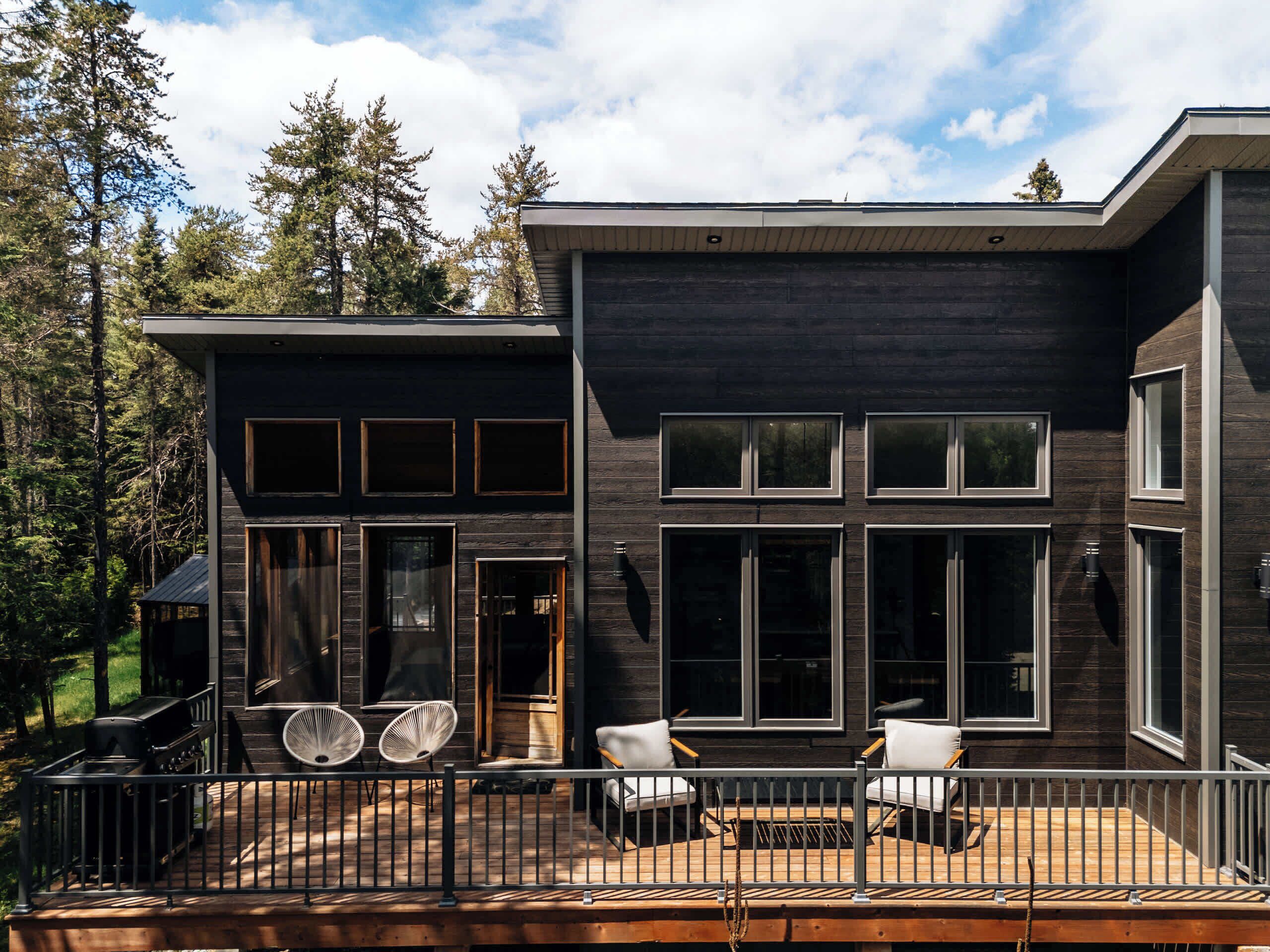 A modern two-story house with a deck, large windows, and a fireplace.